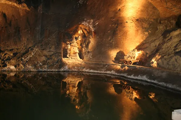 Komora Weimar w Kopalni Soli Wieliczka — podświetlone solne ściany i wózek górniczy odbijające się w podziemnym jeziorku